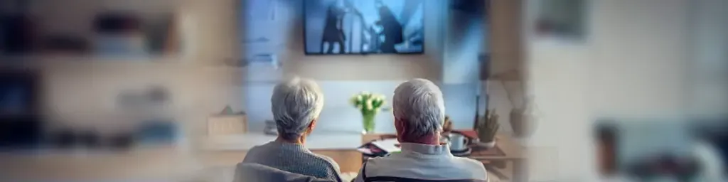 IPTV para Idosos: Entretenimento Fácil e Acessível 1 Idoso assistindo IPTV com controle remoto, Guia simples para configurar IPTV para idosos, Idosos aproveitando IPTV com facilidade